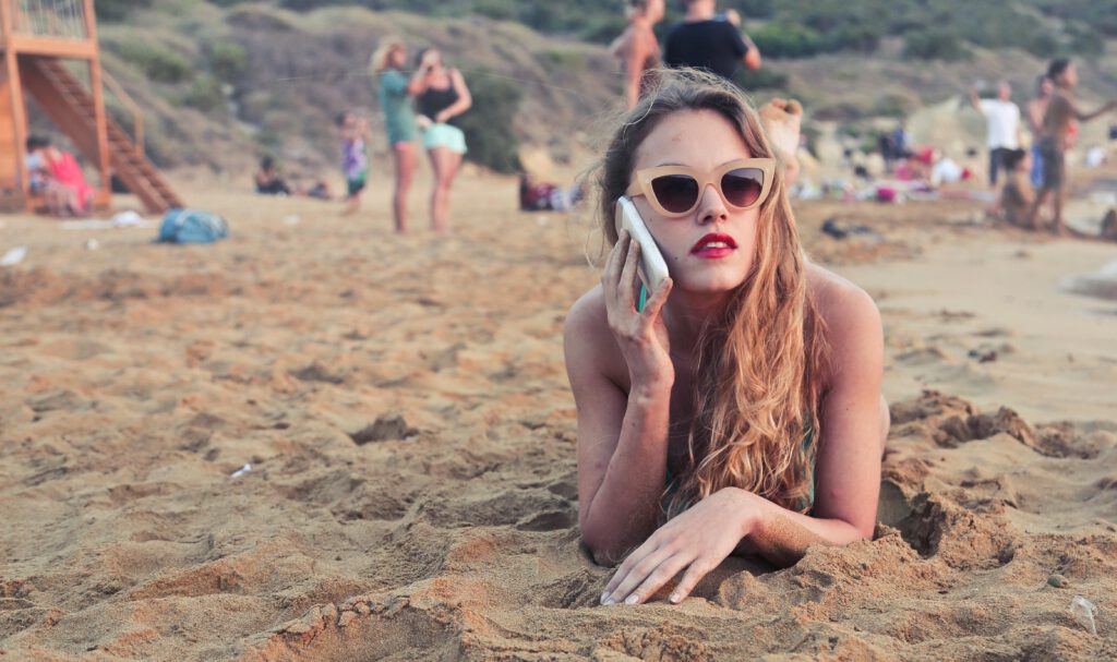 pexels-photo-800292-800292 A woman with sunglasses relaxes on Mgarr Beach in Malta, talking on her smartphone.
